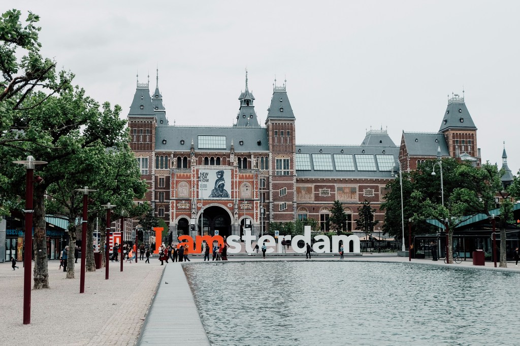 The Rijksmuseum, a prominent art and history museum in Amsterdam, framed by lush greenery.